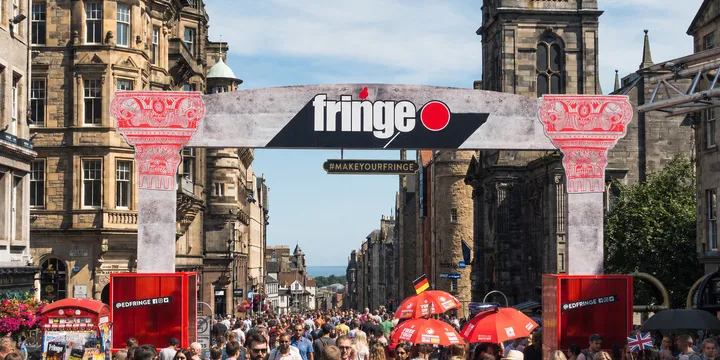 Pancarta callejera del Fringe de Edimburgo sobre una multitud concurrida del festival